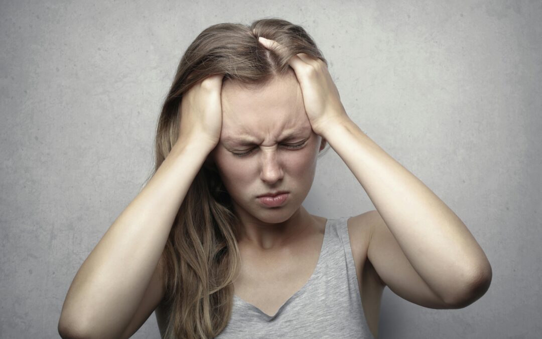 Young woman expressing stress and frustration while holding her head.